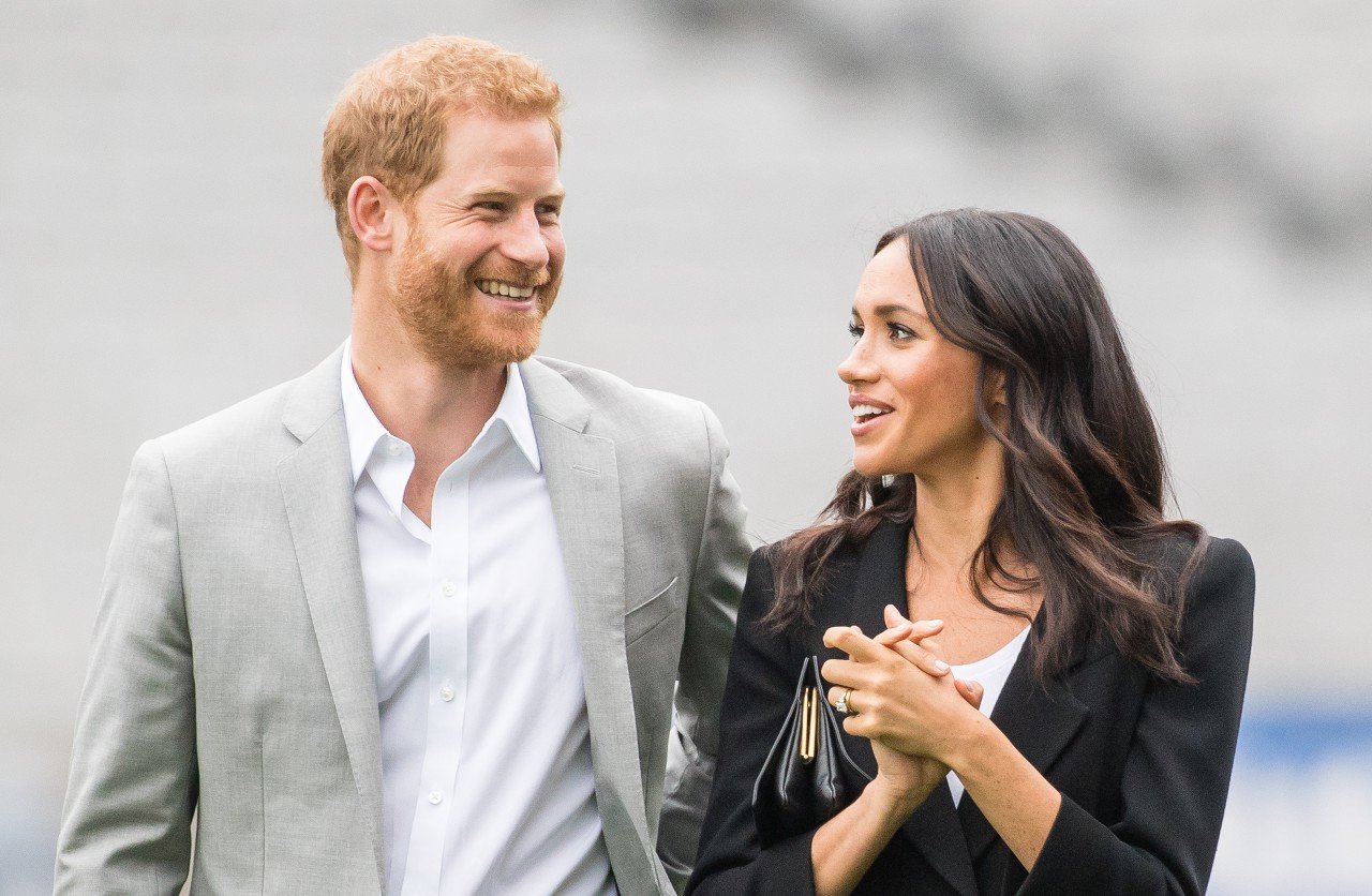 Prince Harry and Meghan Markle laugh together during an event.