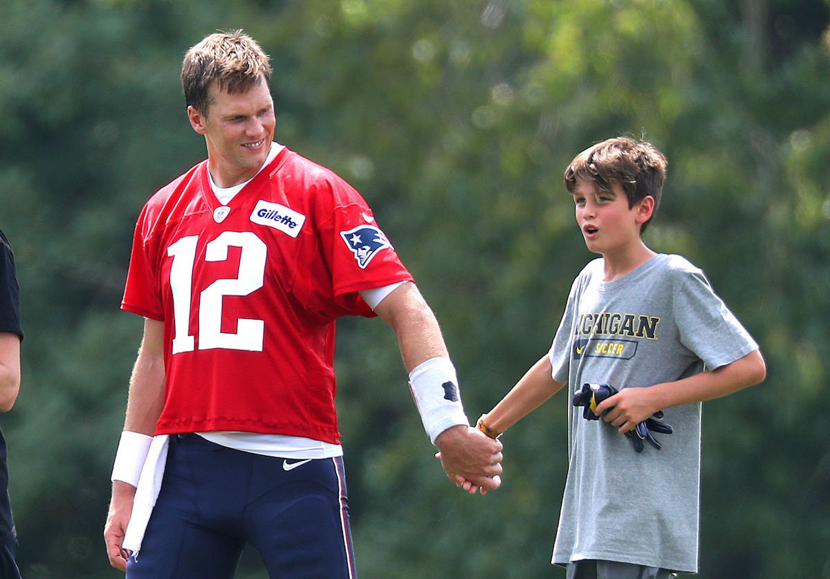 Then-Patriots quarterback Tom Brady walks off the practice field with his oldest son, Jack