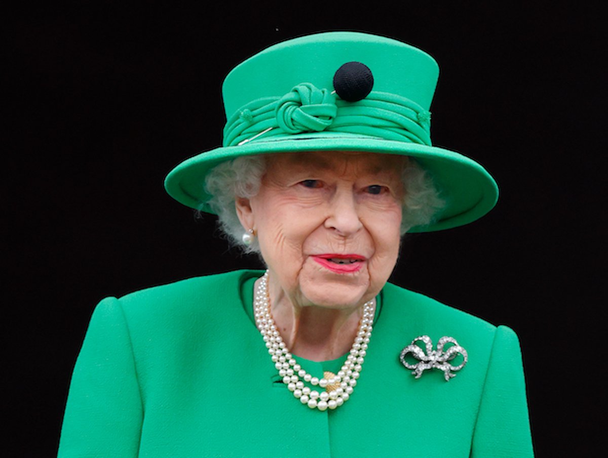 Queen Elizabeth, who had a New Year's Eve tradition where no one went to bed before her, according to her private secretary's memoirs, looks on wearing a green suit and hat
