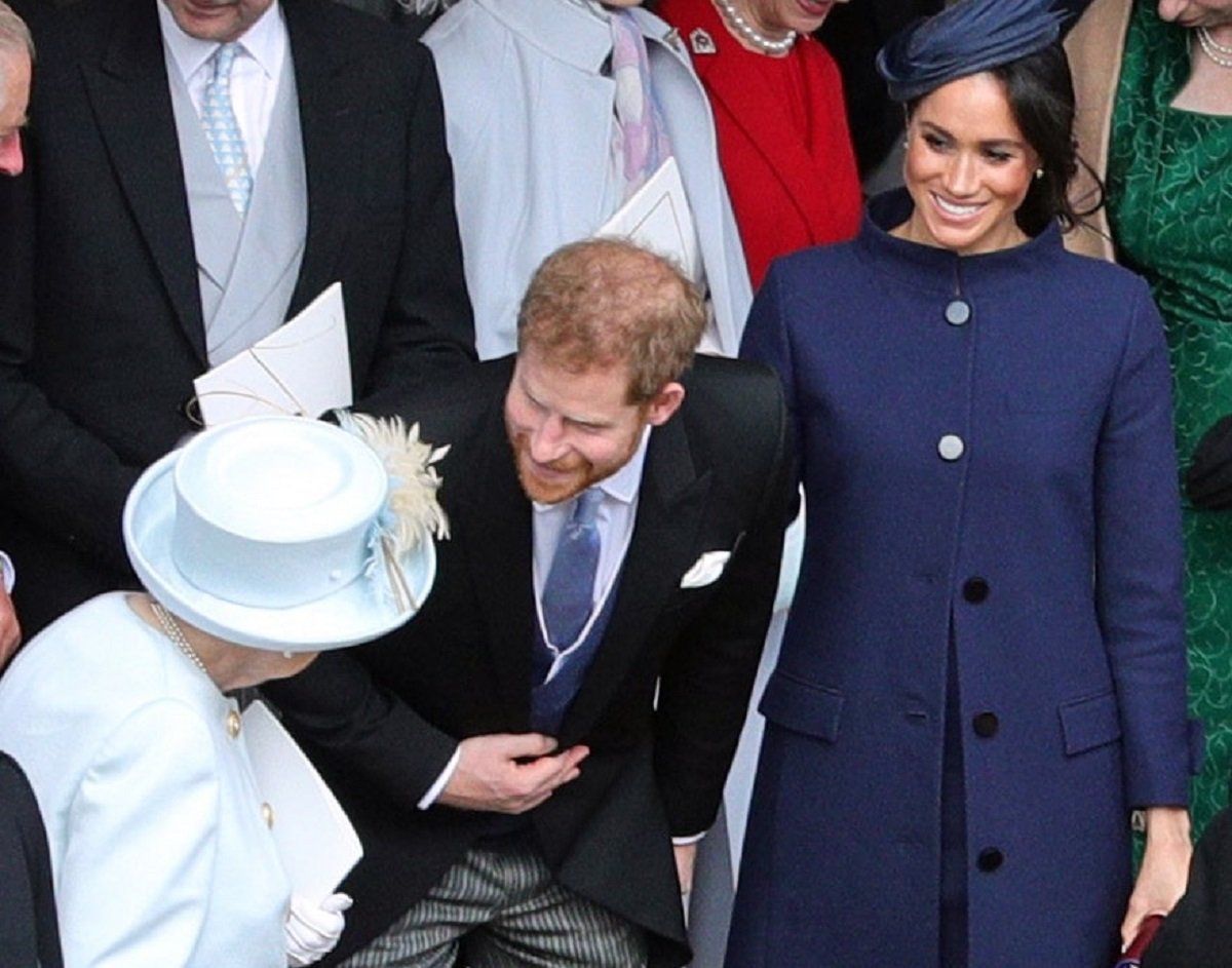 Queen Elizabeth II speaks with Prince Harry and Meghan Markle outside St. George's Chapel following the wedding of Princess Eugenie to Jack Brooksbank