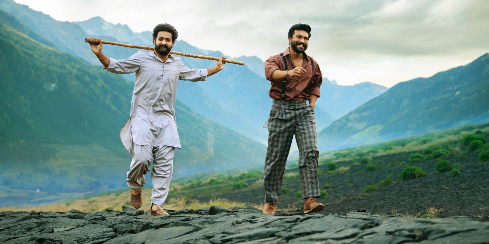 'RRR' N.T. Rama Rao Jr. as Komaram Bheem and Ram Charan Teja as Alluri Sitarama Raju walking along a mountain path smiling