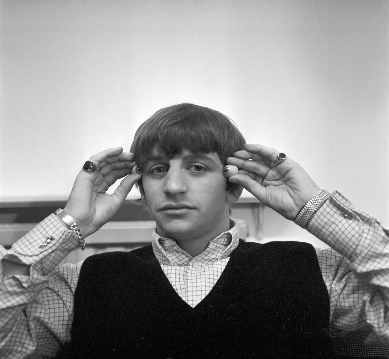 A black and white picture of Ringo Starr holding fake eyeballs next to his face.