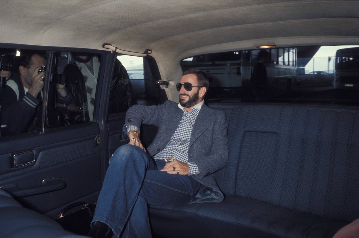 Ringo Starr rides in the back of a car in 1976. Ringo added to his net worth without doing any work thanks to a shrewd business decision.