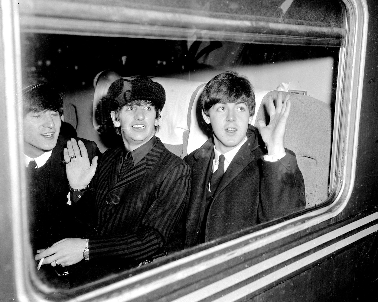 Ringo Starr (middle), John Lennon, and Paul McCartney on board a New York City train in 1964.