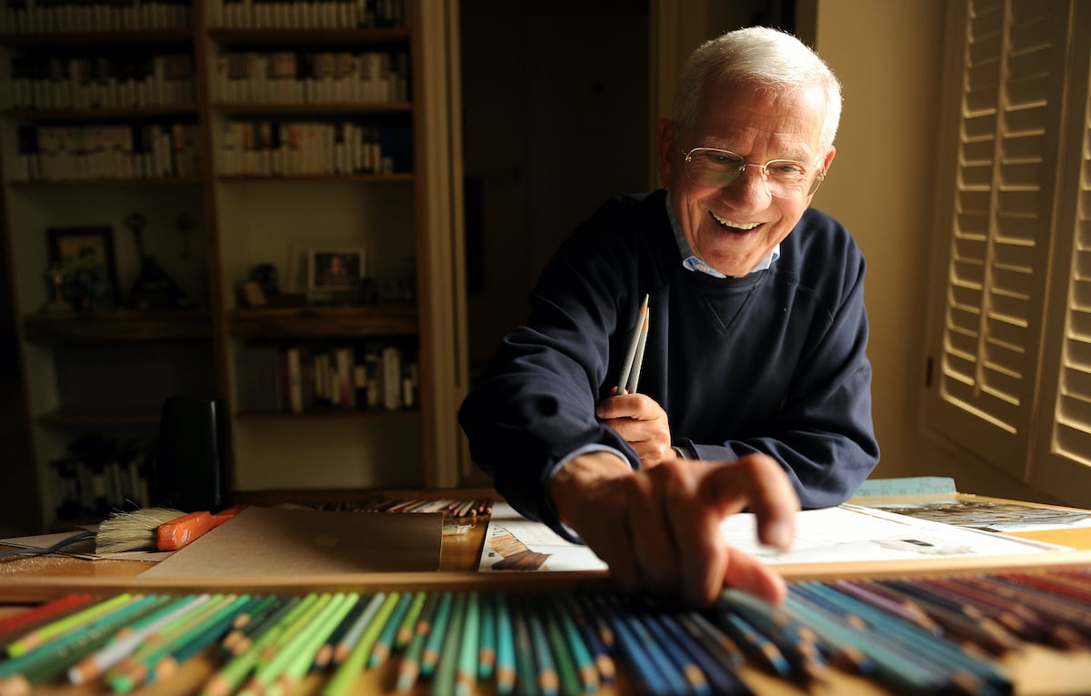 Robert Clary smiling, looking down at colored pencils