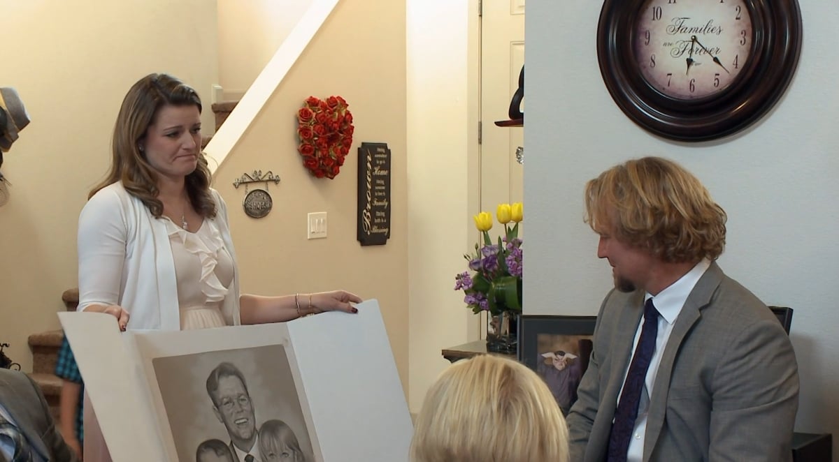 Robyn Brown giving Kody Brown a portrait of him holding her three children, Aurora, Breanna, and Dayton at their adoption party on 'Sister Wives' Season 9 on TLC.