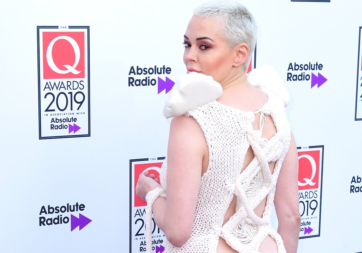 Rose McGowan poses in a white dress on the red carpet.