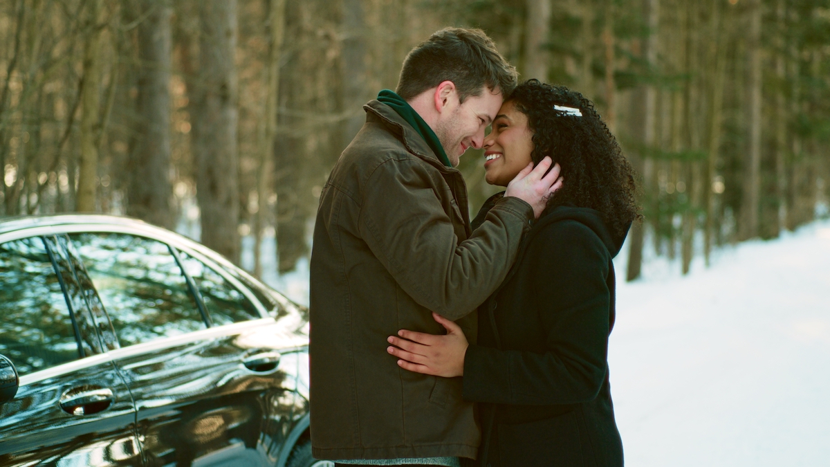 A man kissing a woman in front of a car in UPtv's 'Sappy Holiday'