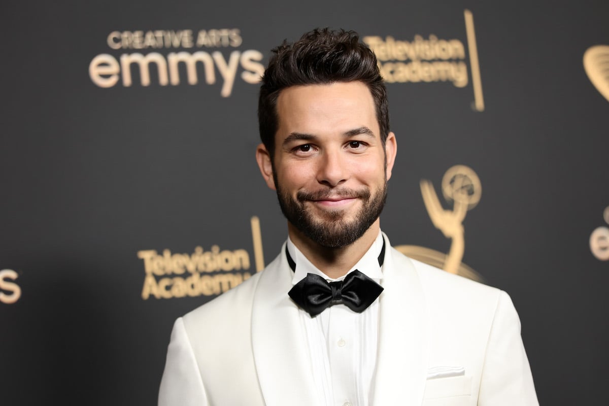 Skylar Astin appears on the Creative Arts Emmys red carpet in a white suit.