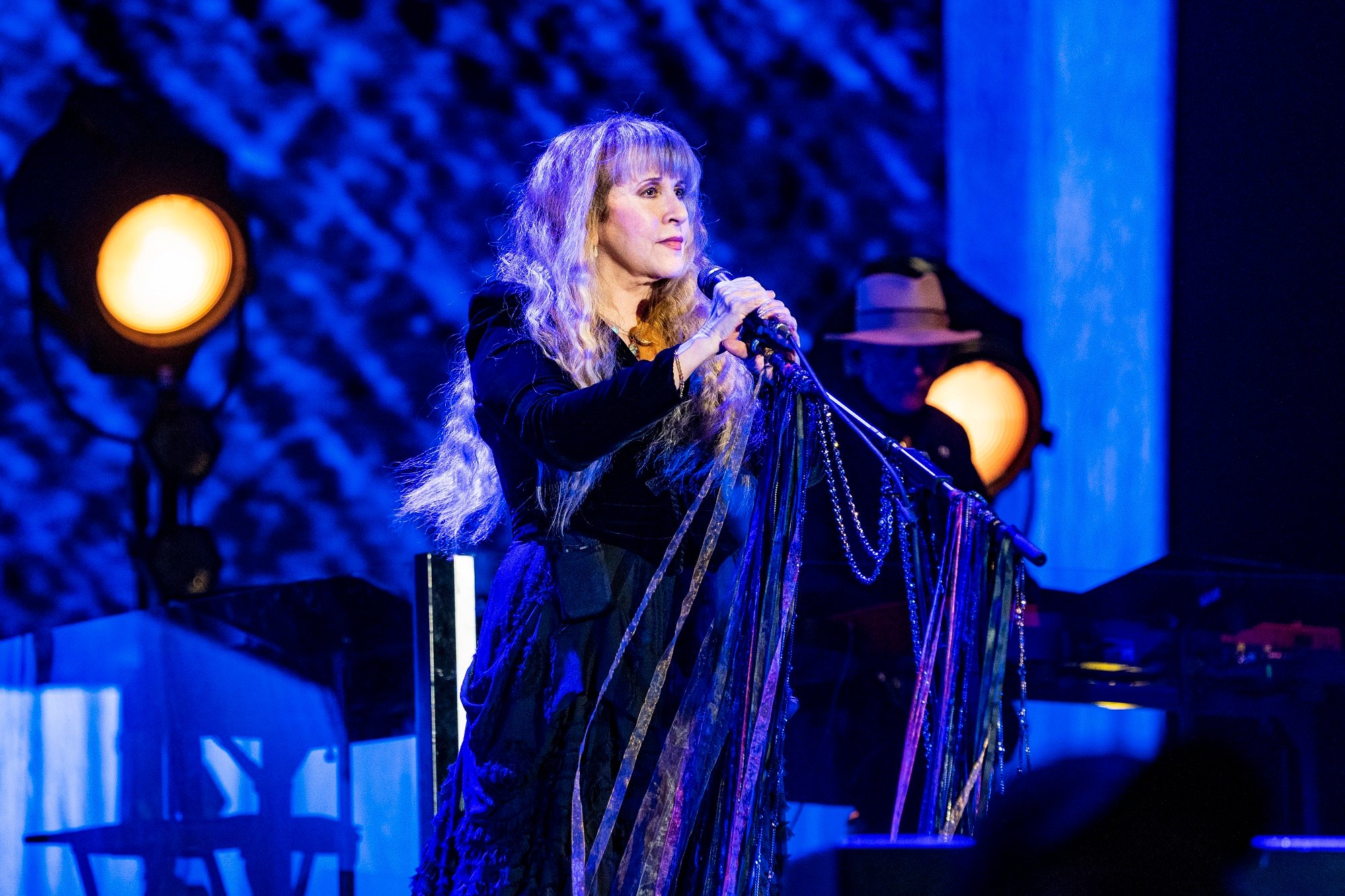 Stevie Nicks holds a microphone stand on stage