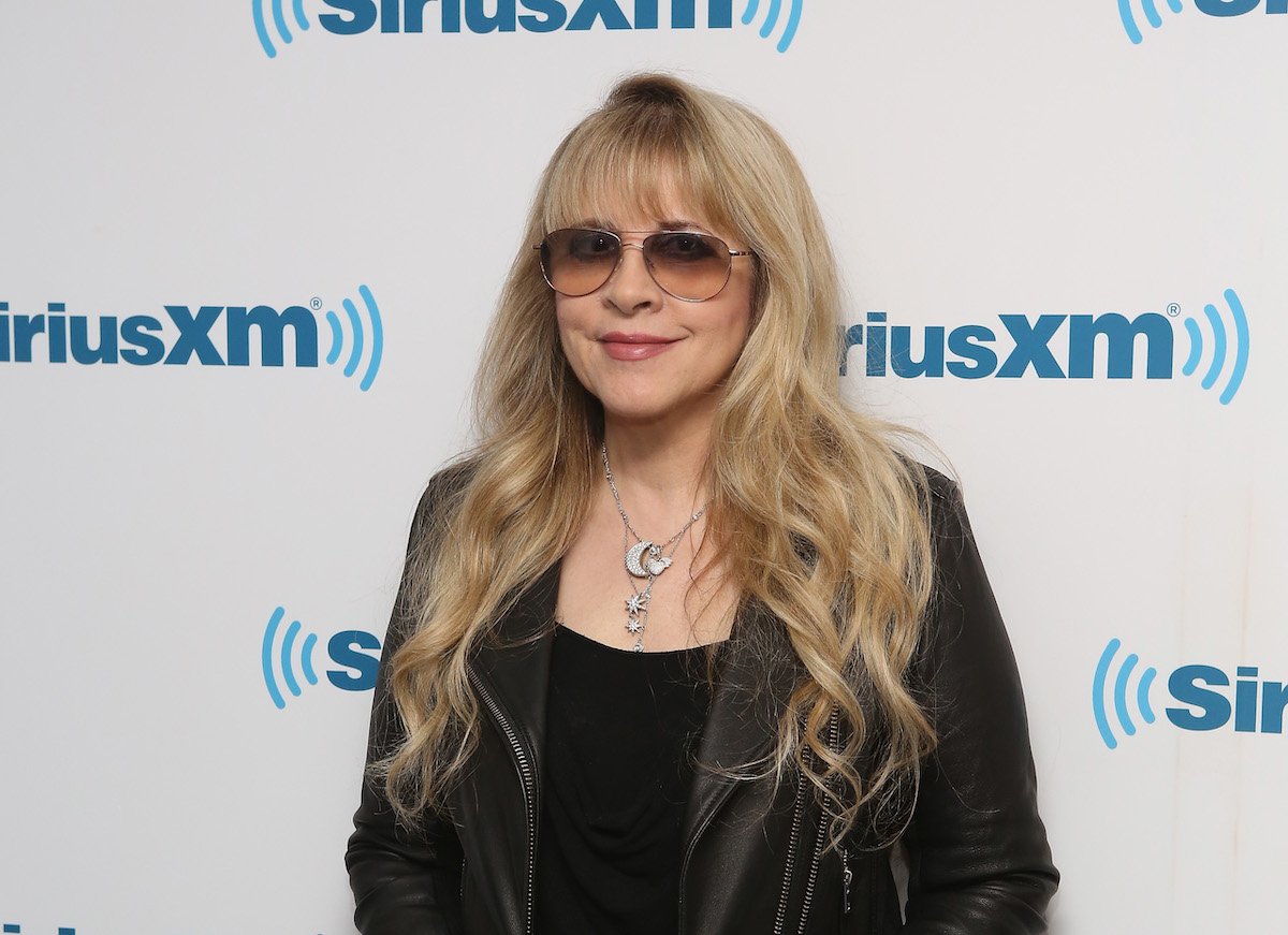Stevie Nicks smiles and poses in sunglasses at an event.