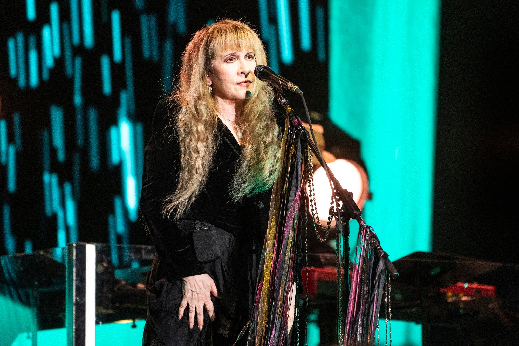 Stevie Nicks stands in front of a microphone on stage