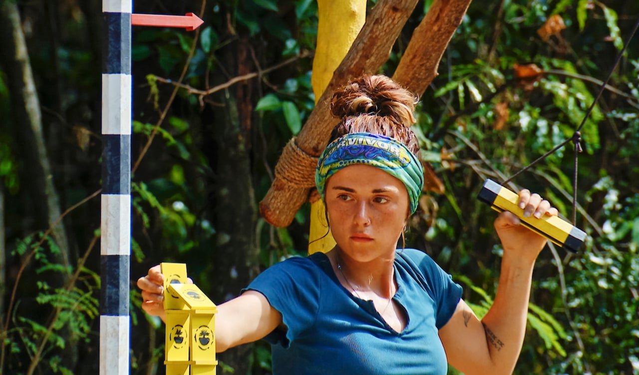 Cassidy Clark holds onto a handle and adds a piece to her tower on 'Survivor 43'.