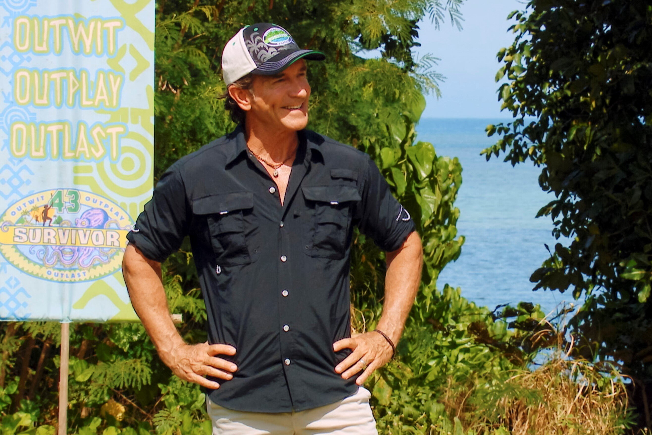 Jeff Probst, who hosts 'Survivor' on CBS, wears a black button-up shirt with rolled up sleeves, white pants, and a black and white 'Survivor' hat.