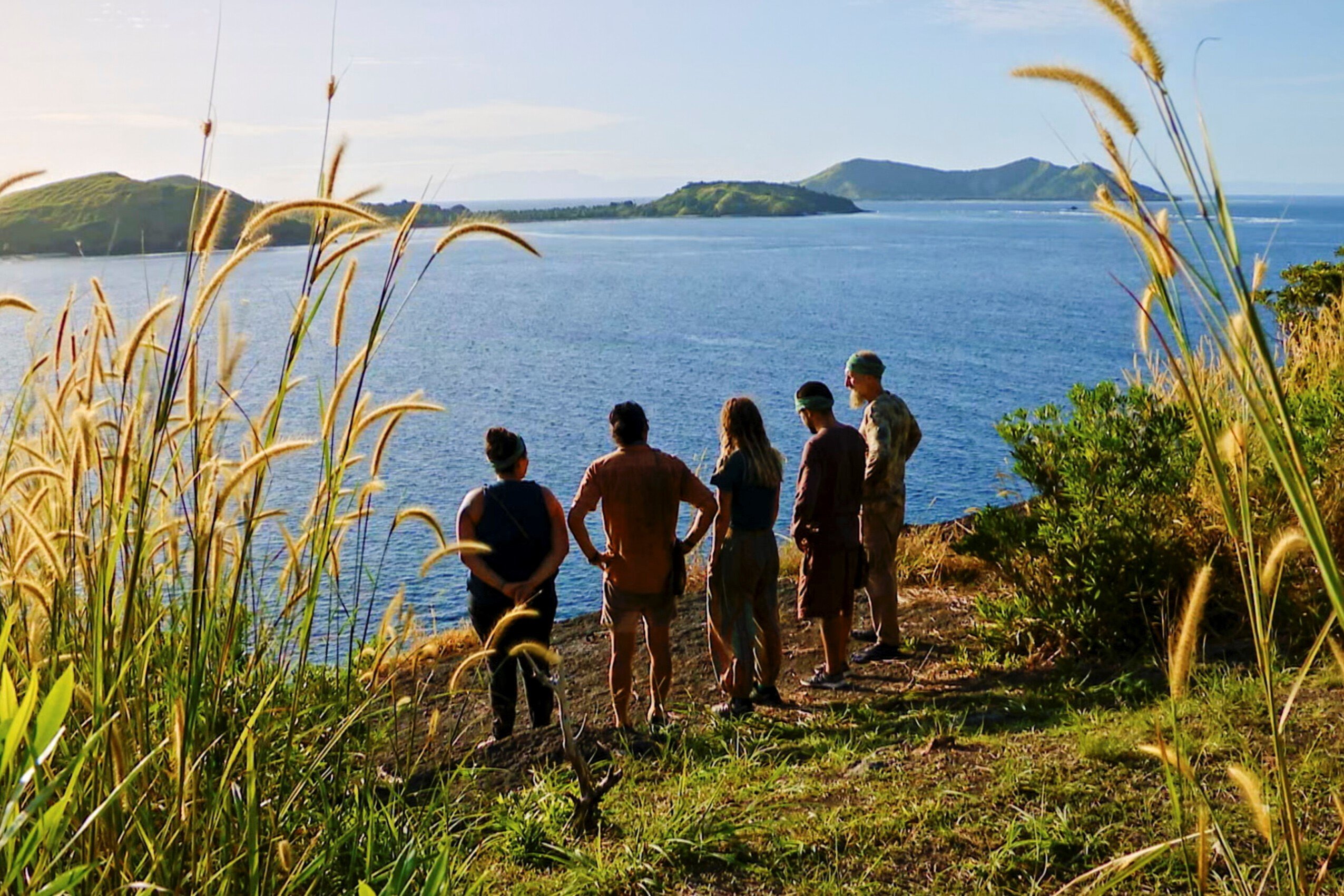 Karla Cruz Godoy, Owen Knight, Cassidy Clark, Jesse Lopez, and Mike Gabler, who star in the 'Survivor' Season 43 finale tonight, Dec. 14, stand on the edge of a cliff, looking out at the ocean.