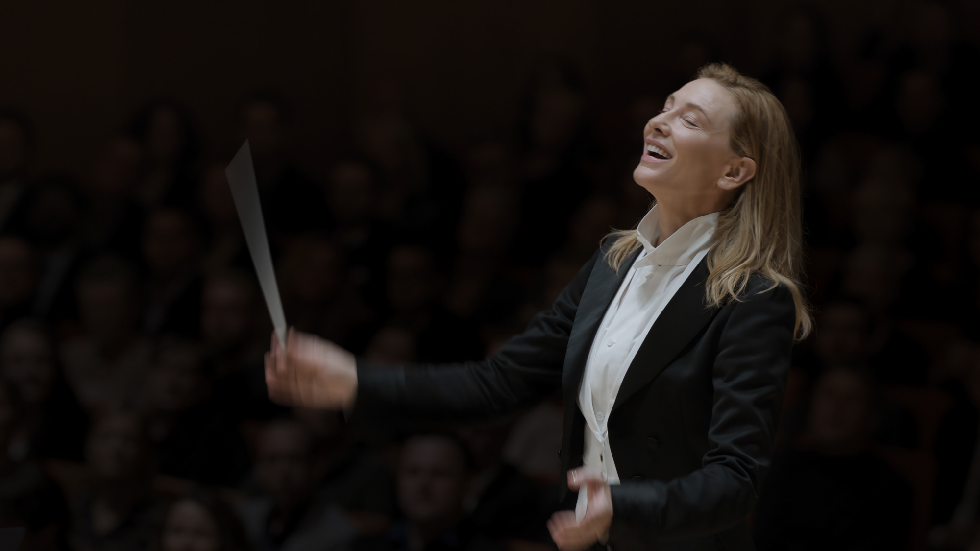 'TÁR' Cate Blanchett as Lydia Tár smiling wearing a suit while conducting an orchestra