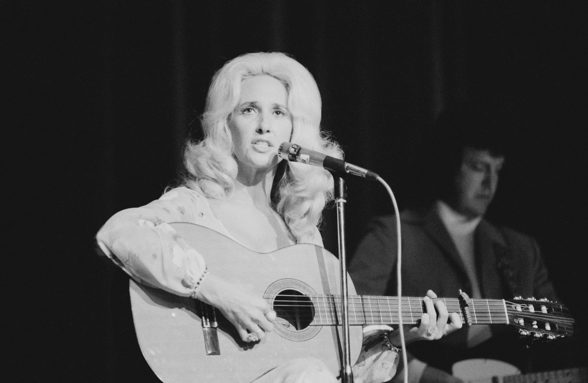 A black-and-white photo of Tammy Wynette playing guitar
