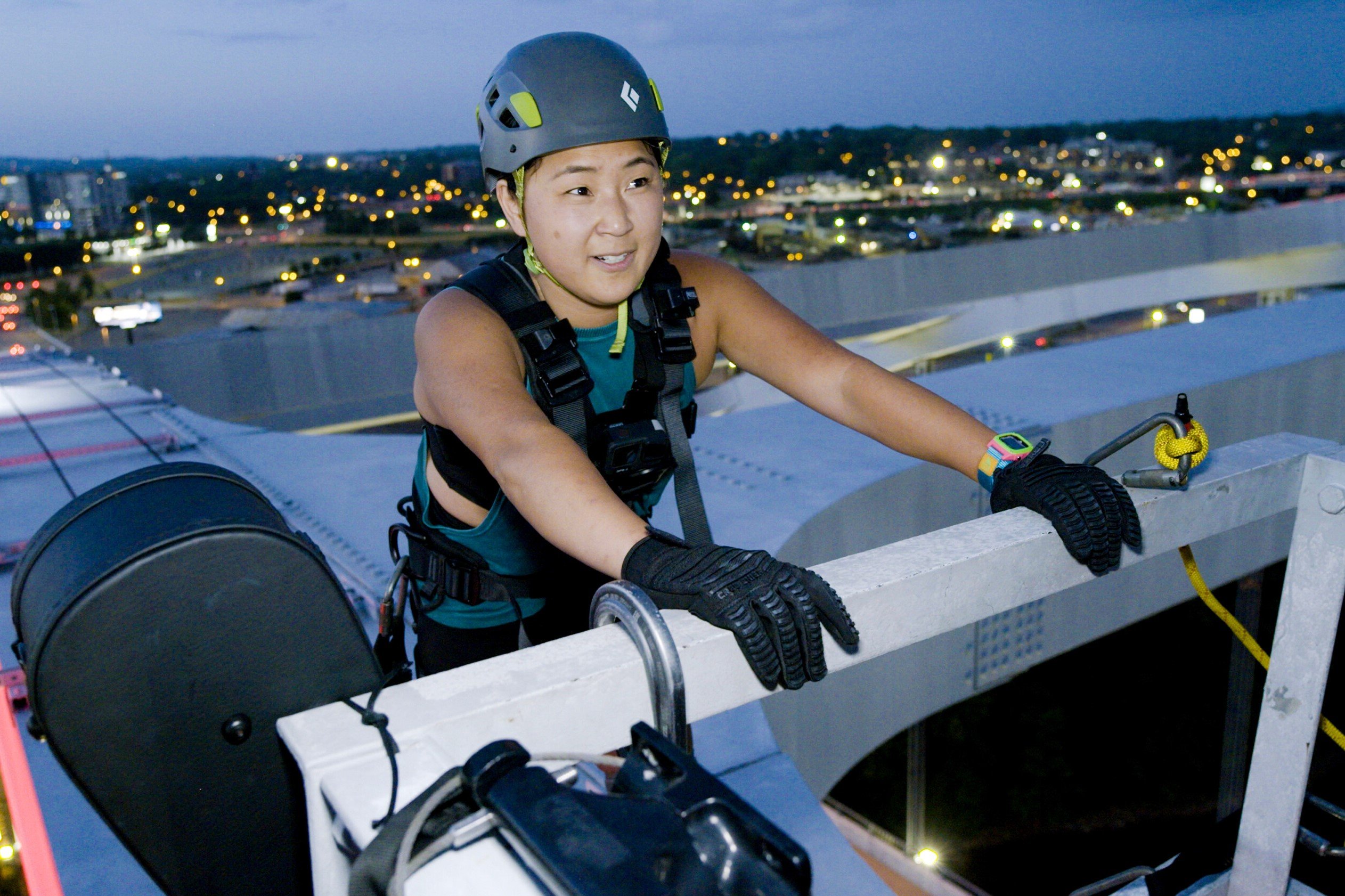 Emily Bushnell, who stars in the finale of 'The Amazing Race 34' tonight, Dec. 7, on CBS, wears a teal tank top, black pants, and climbing gear as she stands on top of a tall white structure.