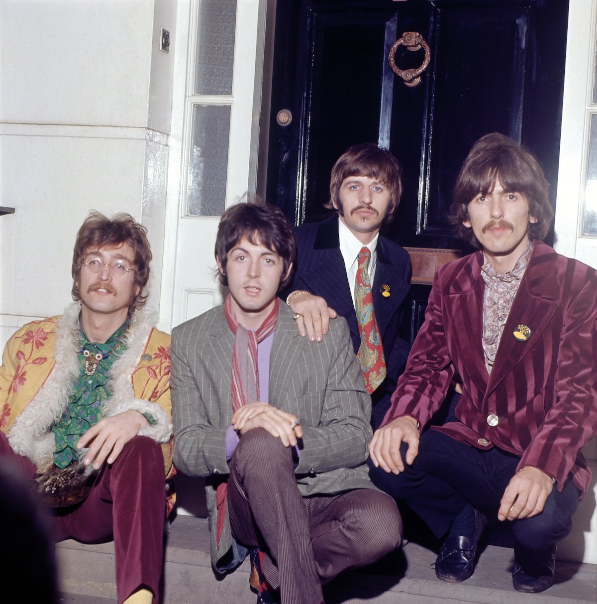 The Beatles Ringo Starr, John Lennon, Paul McCartney and George Harrison sit on a stoop in front of a door