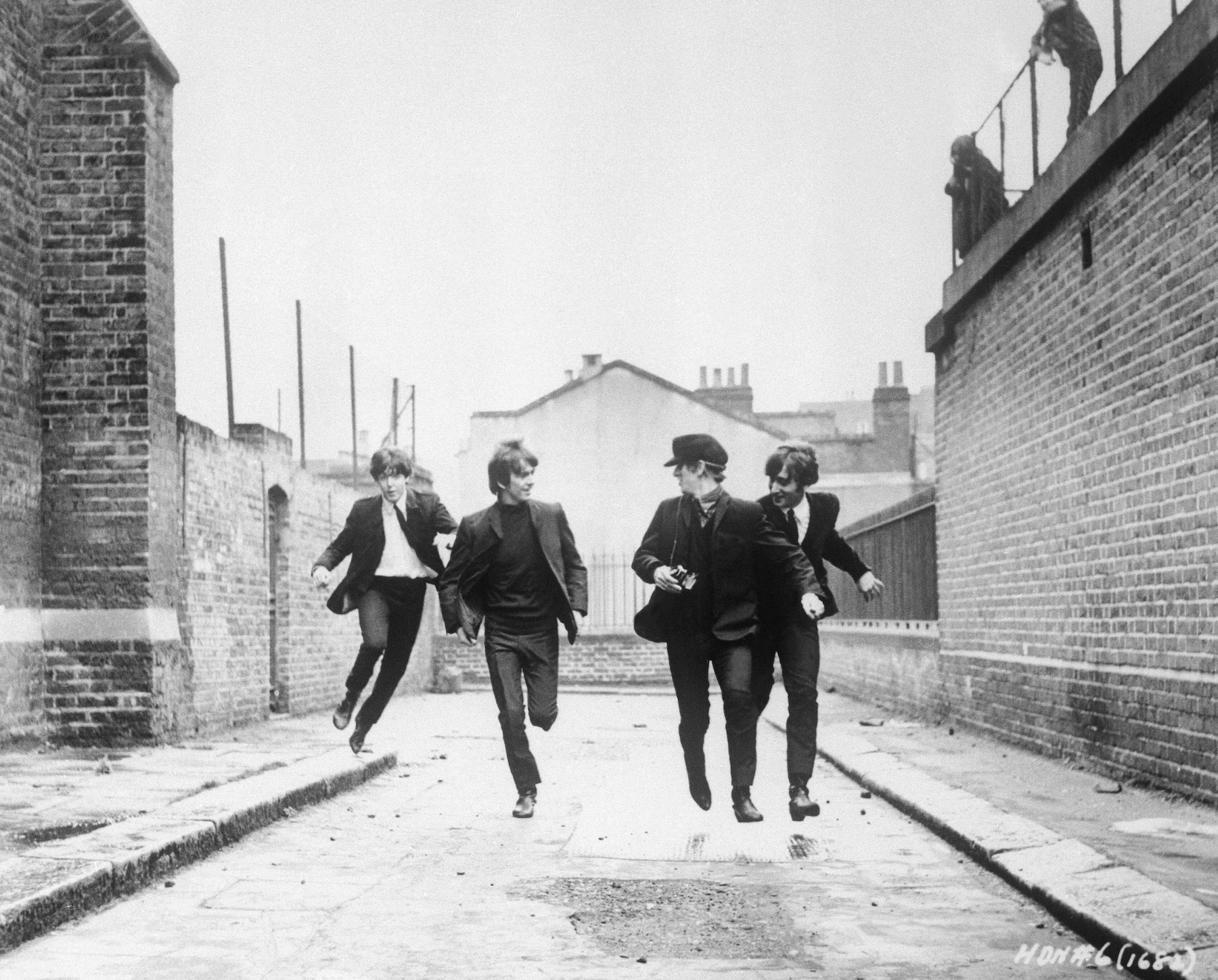 From left to right, Paul McCartney, George Harrison, John Lennon, and Ringo Starr run down an empty London street