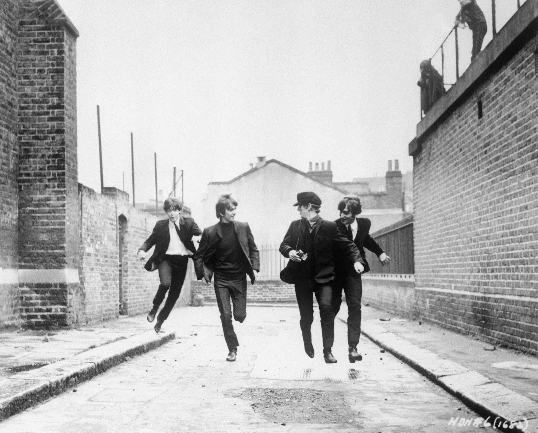 From left to right, Paul McCartney, George Harrison, John Lennon, and Ringo Starr run down an empty London street