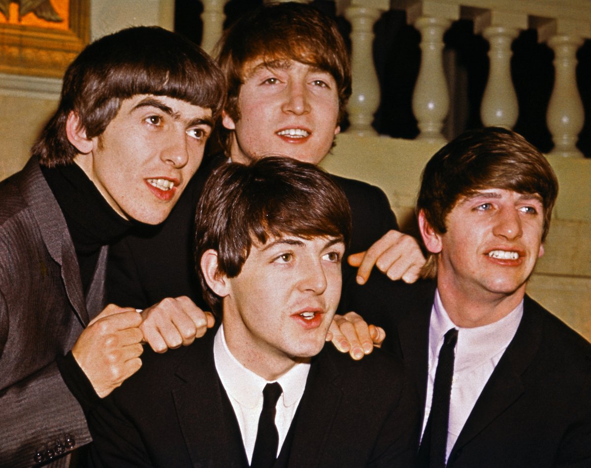 The Beatles smile with their mop top haircuts wearing suits