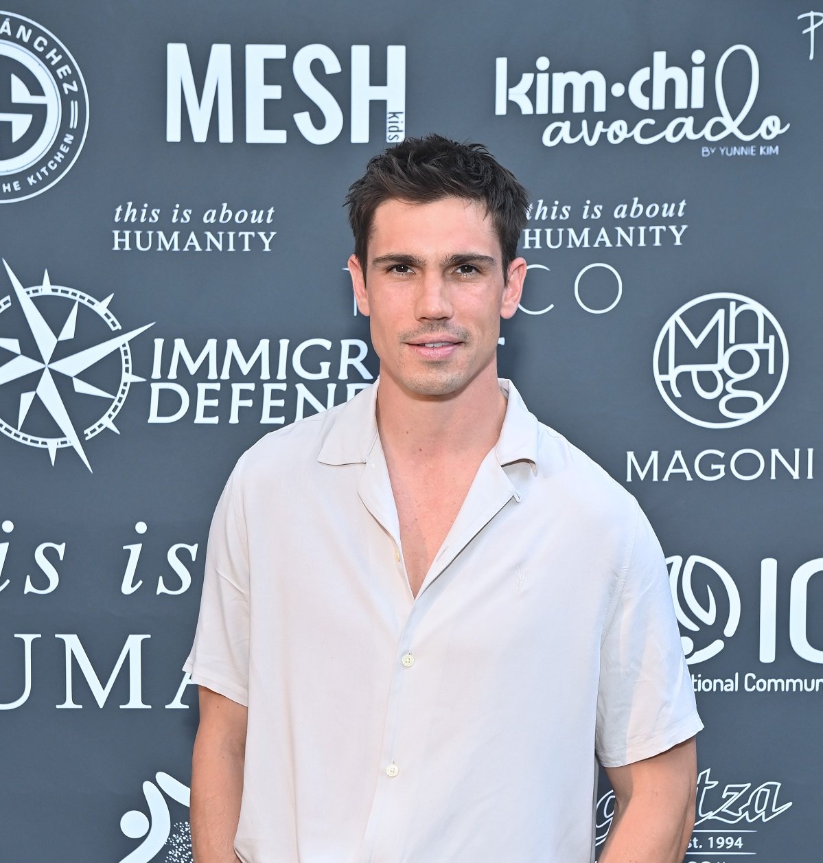 'The Bold and the Beautiful' star Tanner Novlan wearing a white shirt and posing during a red carpet appearance.