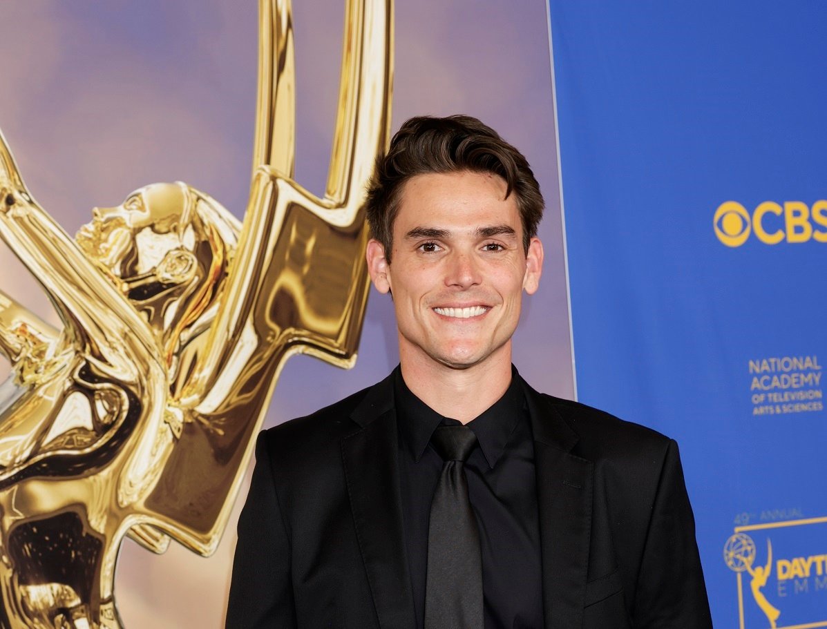 'The Young and the Restless' star Mark Grossman wearing a black suite and posing in front of a Daytime Emmy statue.