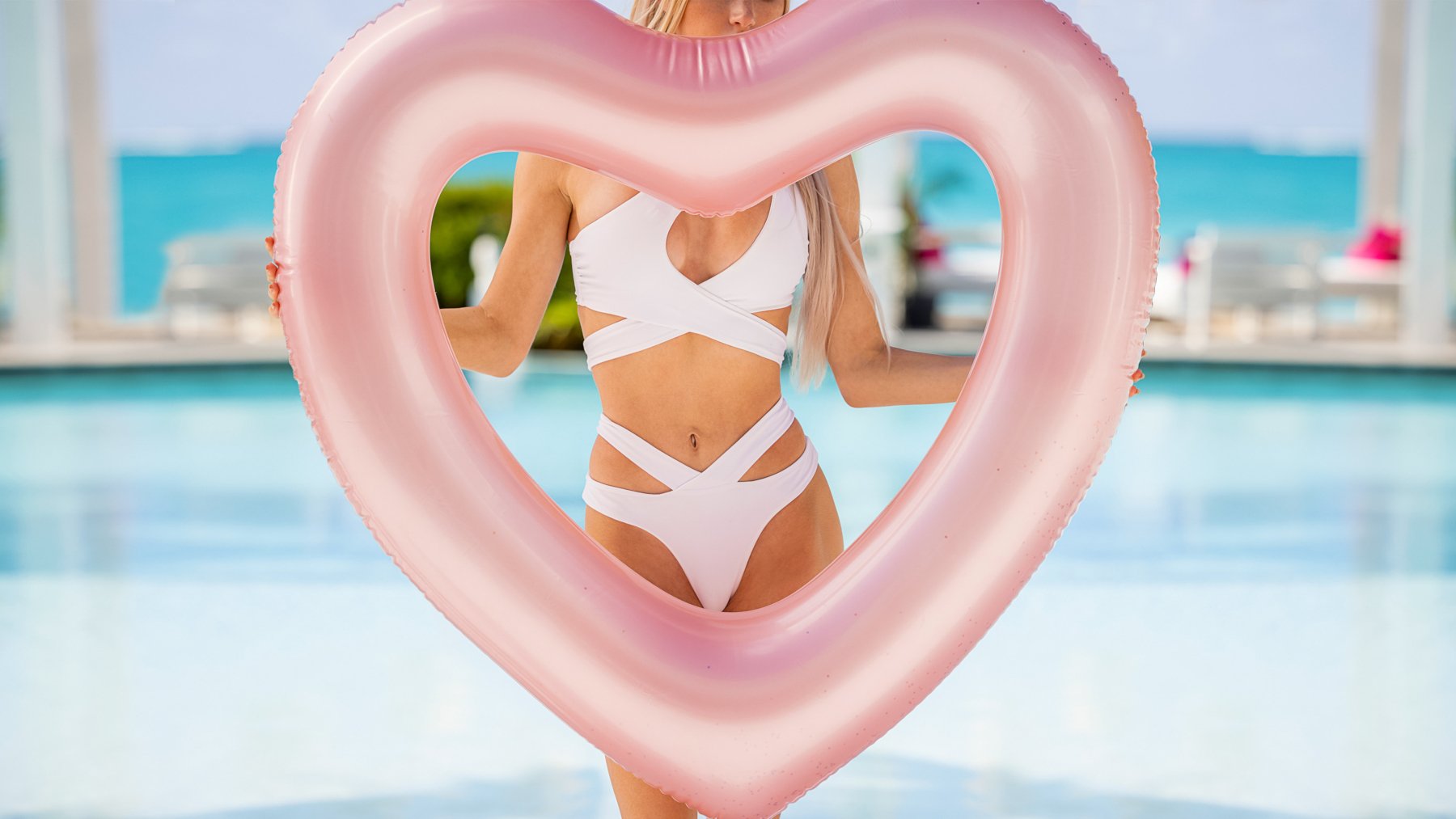 Promotional photo for 'Too Hot to Handle' Season 4. It features a woman in a white bikini, and she's holding a pink heart-shaped balloon, which is covering her face.
