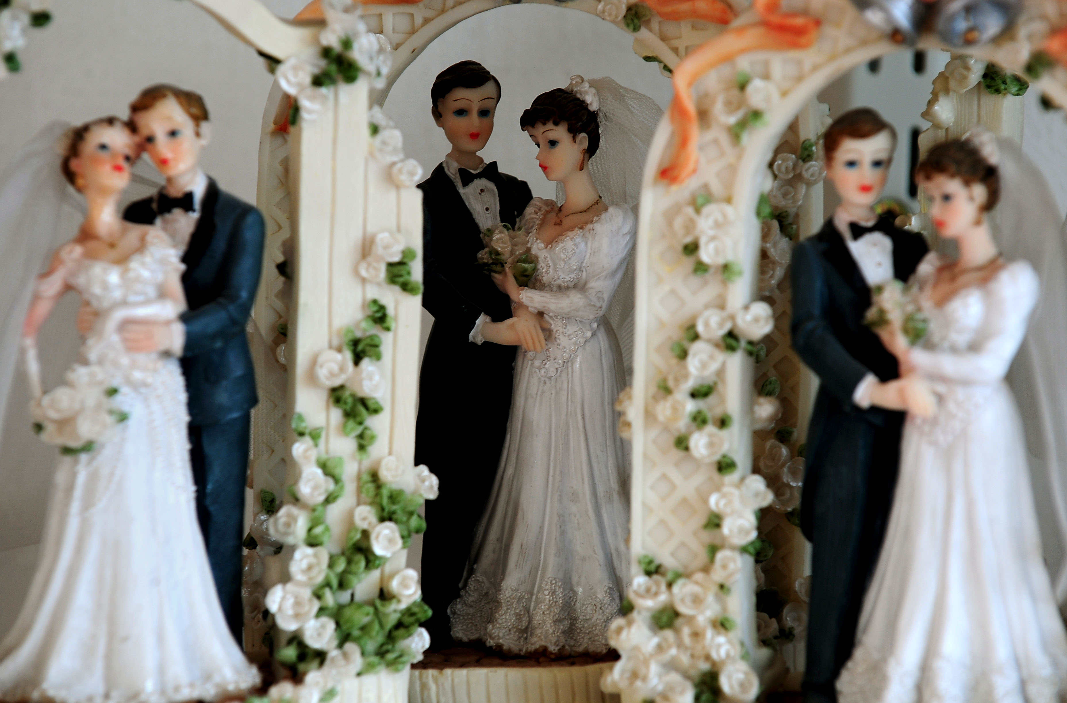 a trio of bride and groom figures on a wedding cake