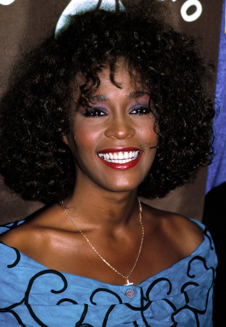 Whitney Houston smiles with red lipstick on