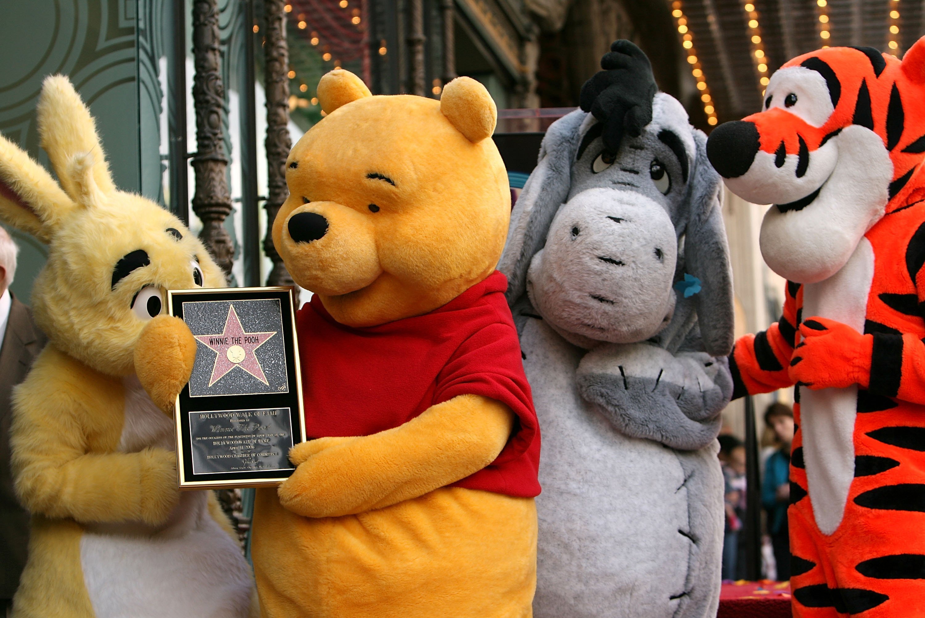'Winnie the Pooh' characters Rabbit, Winnie the Pooh, Eeyore, and Tigger posing together after receiving a star on the Hollywood Walk of Fame.