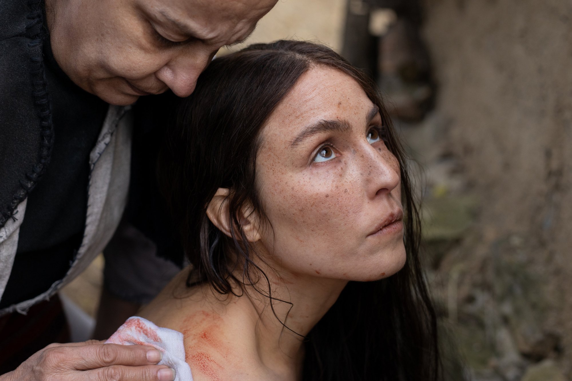 'You Won't Be Alone' Noomi Rapace as Bosilka looking up while getting blood washed off of her back by another woman