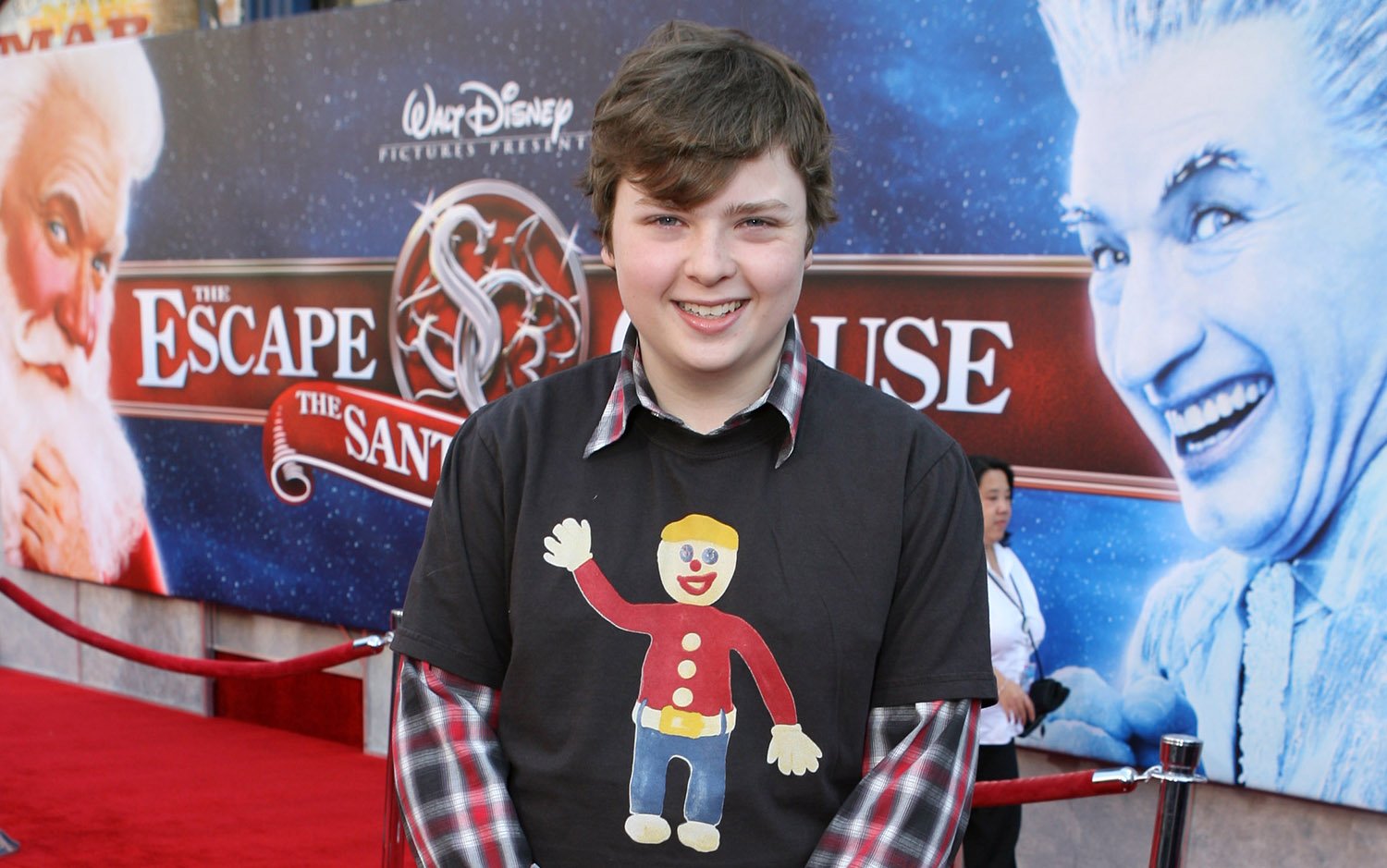 Spencer Breslin, who plays Curtis the Elf, poses for a photo in a plaid shirt underneath a gingerbread man tee at The Santa Clause 3 premiere