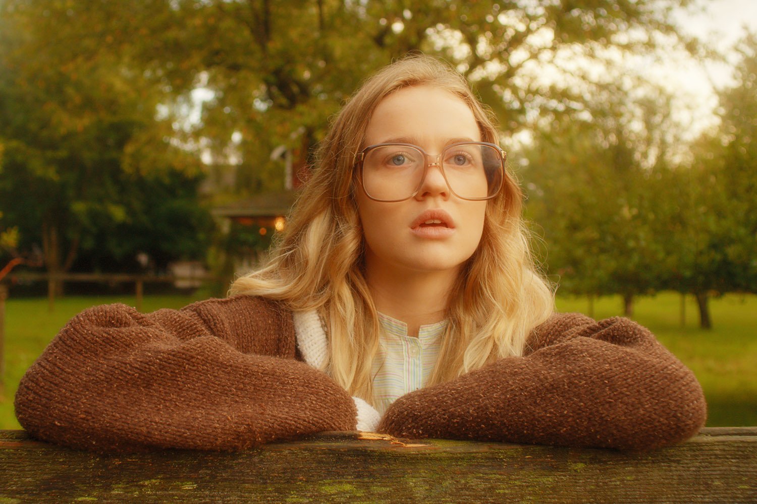 Firefly Lane star Roan Curtis as Kate leaning over a fence and staring ahead in awe