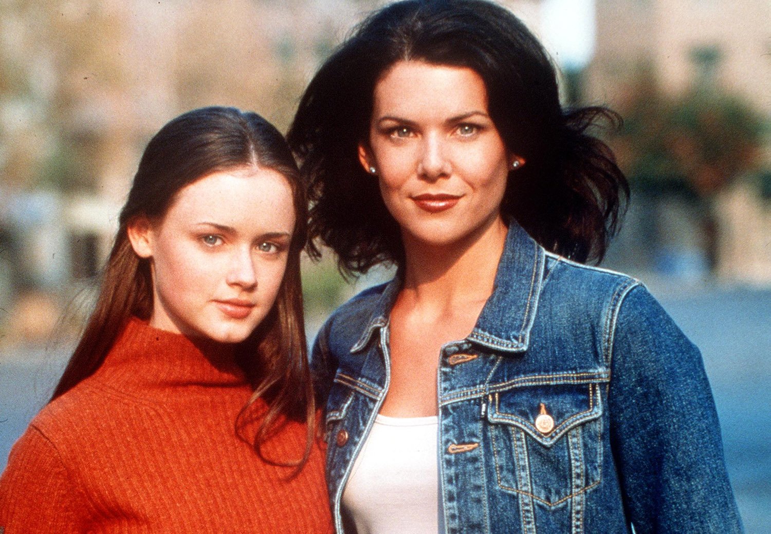 Gilmore Girls book series: Alexis Bledel as Rory Gilmore in an orange sweater and Lauren Graham as Lorelai Gilmore in a denim jacket in a promo image for Gilmore Girls
