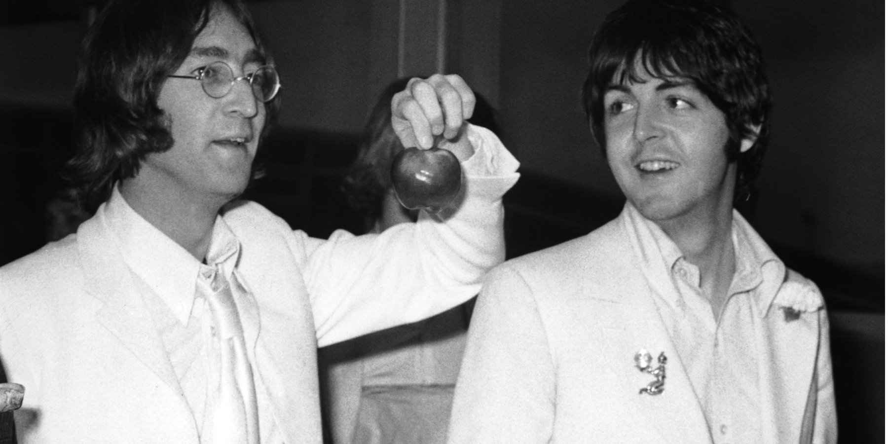 John Lennon and Paul McCartney both dressed in white and carrying apples to promote their new company Apple Corps.