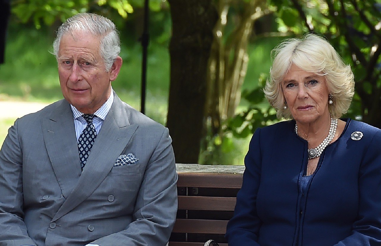 King Charles and Queen Camilla sit side-by-side on a bench.