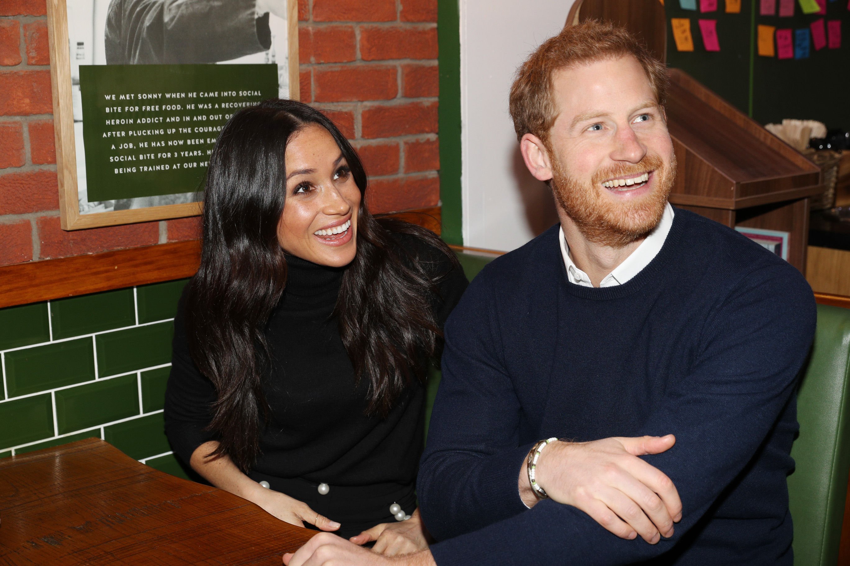 Meghan Markle and Prince Harry smile while sitting in a both during their visit to Social Bite on February 13, 2018 in Edinburgh, Scotland.