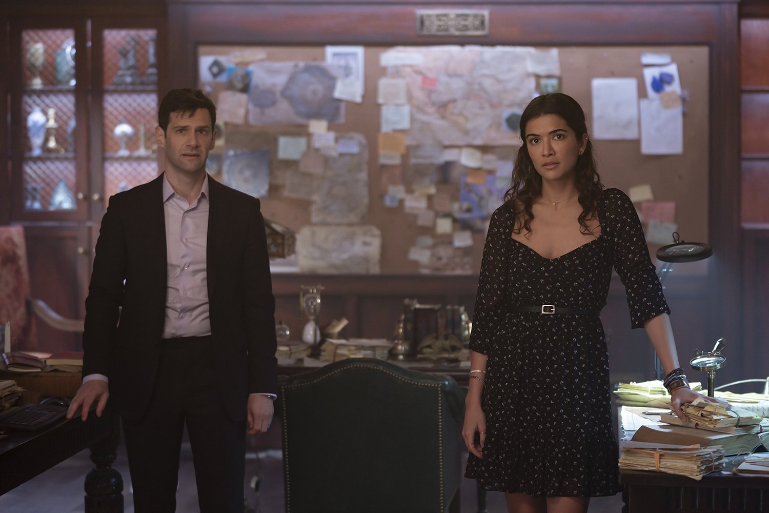 Justin Bartha as Riley Poole and Lisette Olivera as Jess Valenzuela stand in front of an investigation board in National Treasure: Edge of History, a sequel to the movies