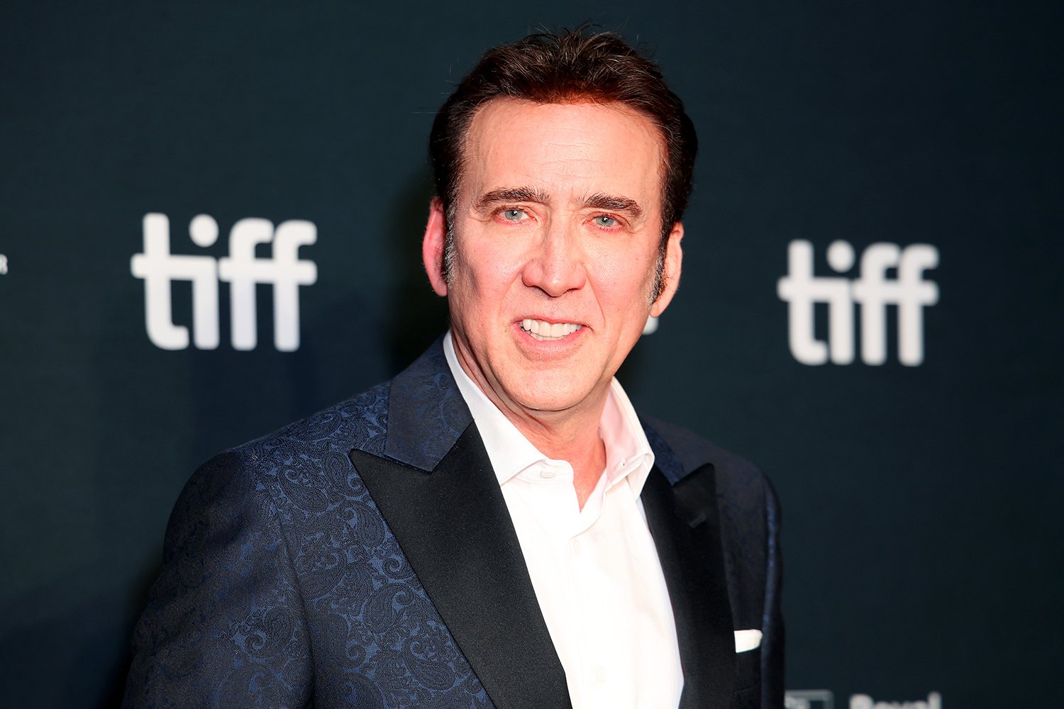 National Treasure star Nicolas Cage smiles in a blue tuxedo at the 2022 Toronto International Film Festival