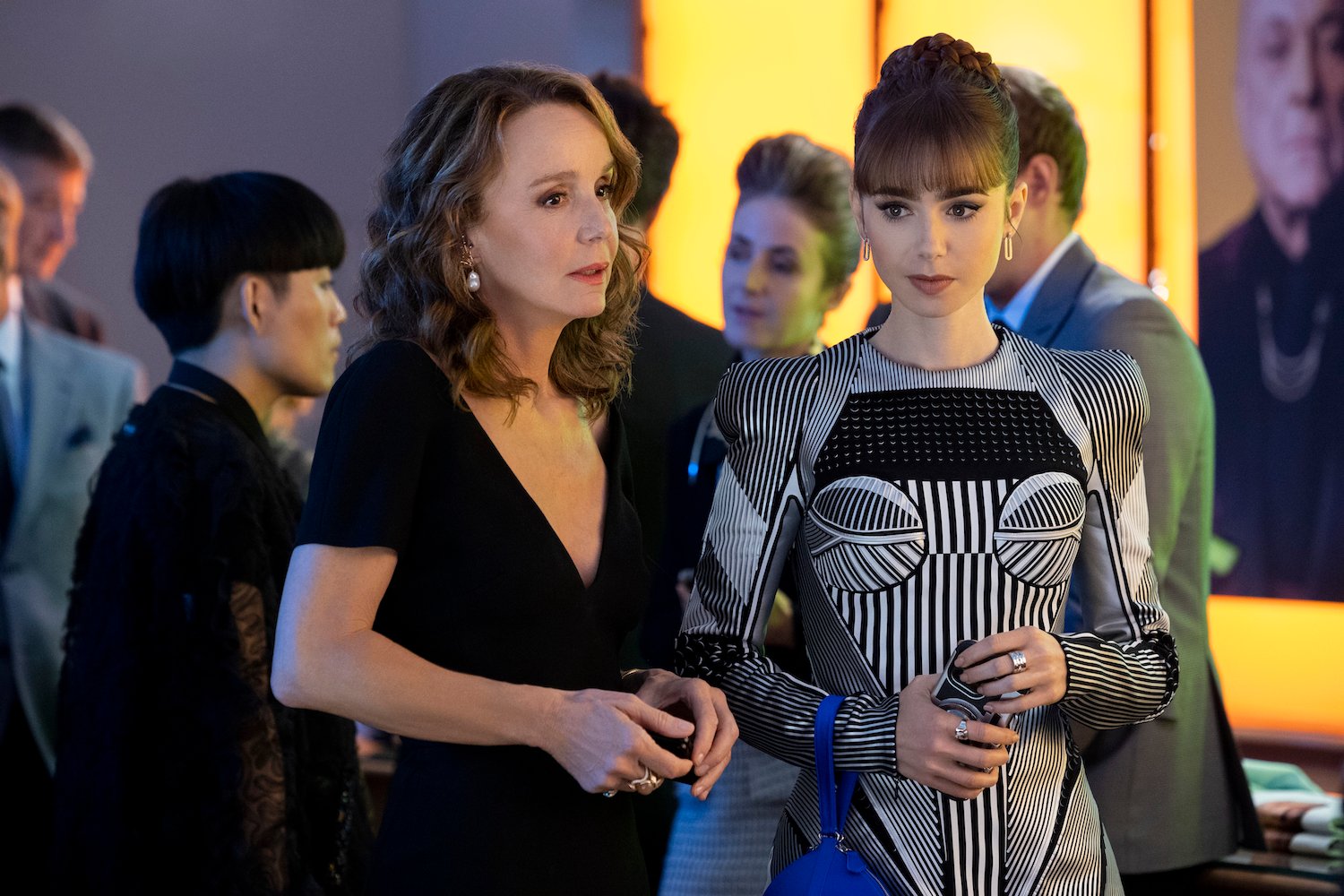Philippine Leroy-Beaulieu as Sylvie Grateau, Lily Collins as Emily wearing a black and white dress, in a scene from 'Emily in Paris,' one of our picks for some of the most overrated shows on Netflix.