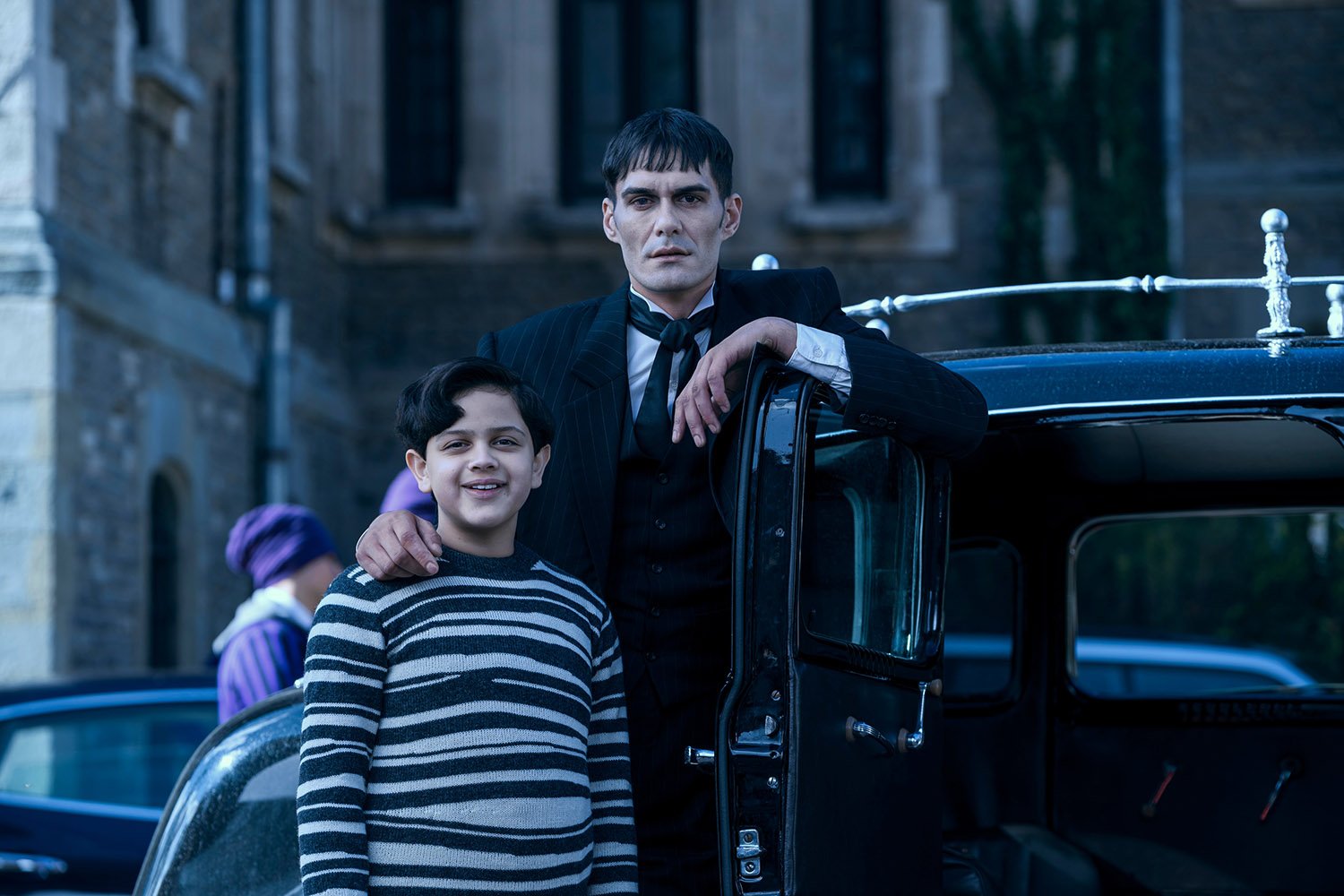 Wednesday: Issac Ordonez as Pugsley Addams standing beside George Burcea as Lurch as they wait at the family car