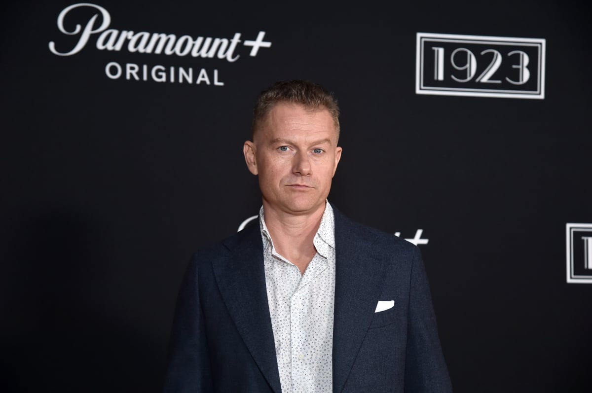 1923 star James Badge Dale wears a button-down shirt and blue suit jacket.