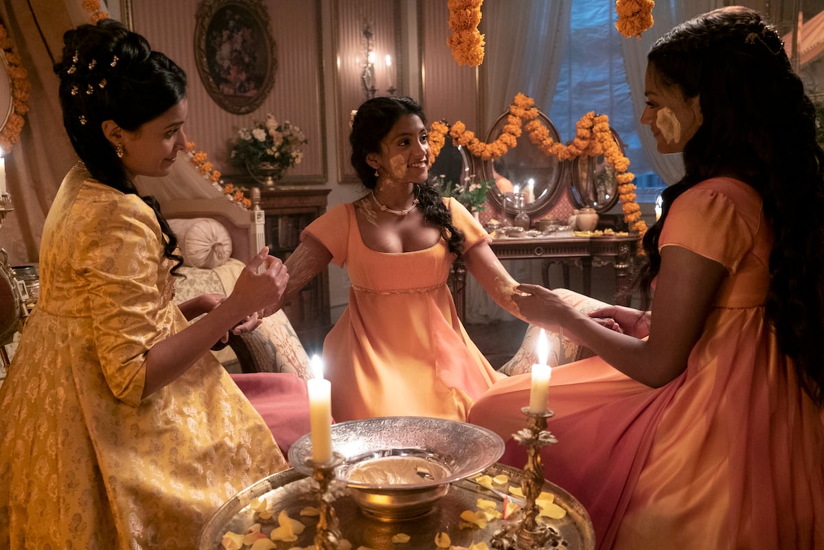 'Bridgerton' cast members Shelley Conn as Mary Sharma, Charithra Chandran as Edwina Sharma, Simone Ashley as Kate Sharma applying turmeric paste