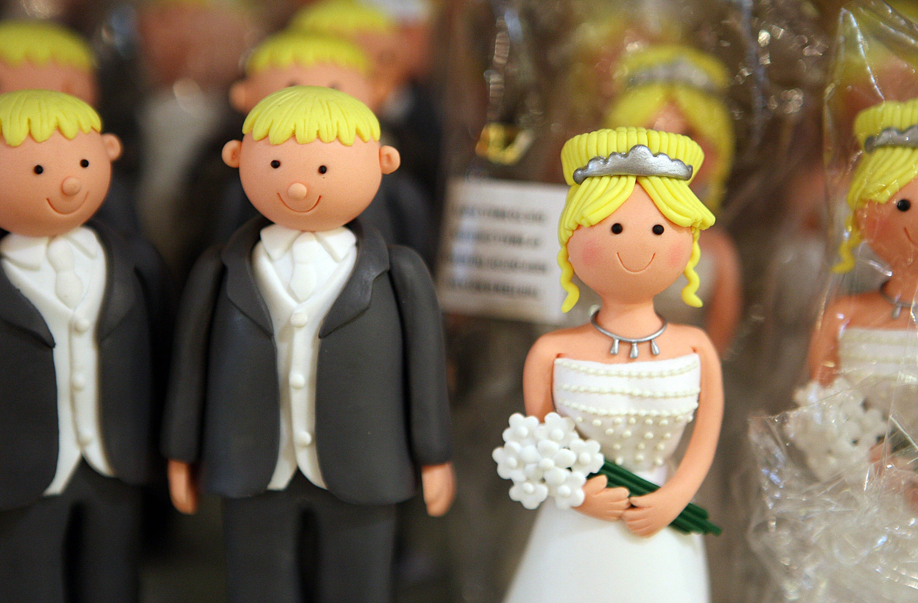 A bride wedding cake topper with two groom figures, similar to the arrangement on the new TLC show 'Seeking Brokther Husband'