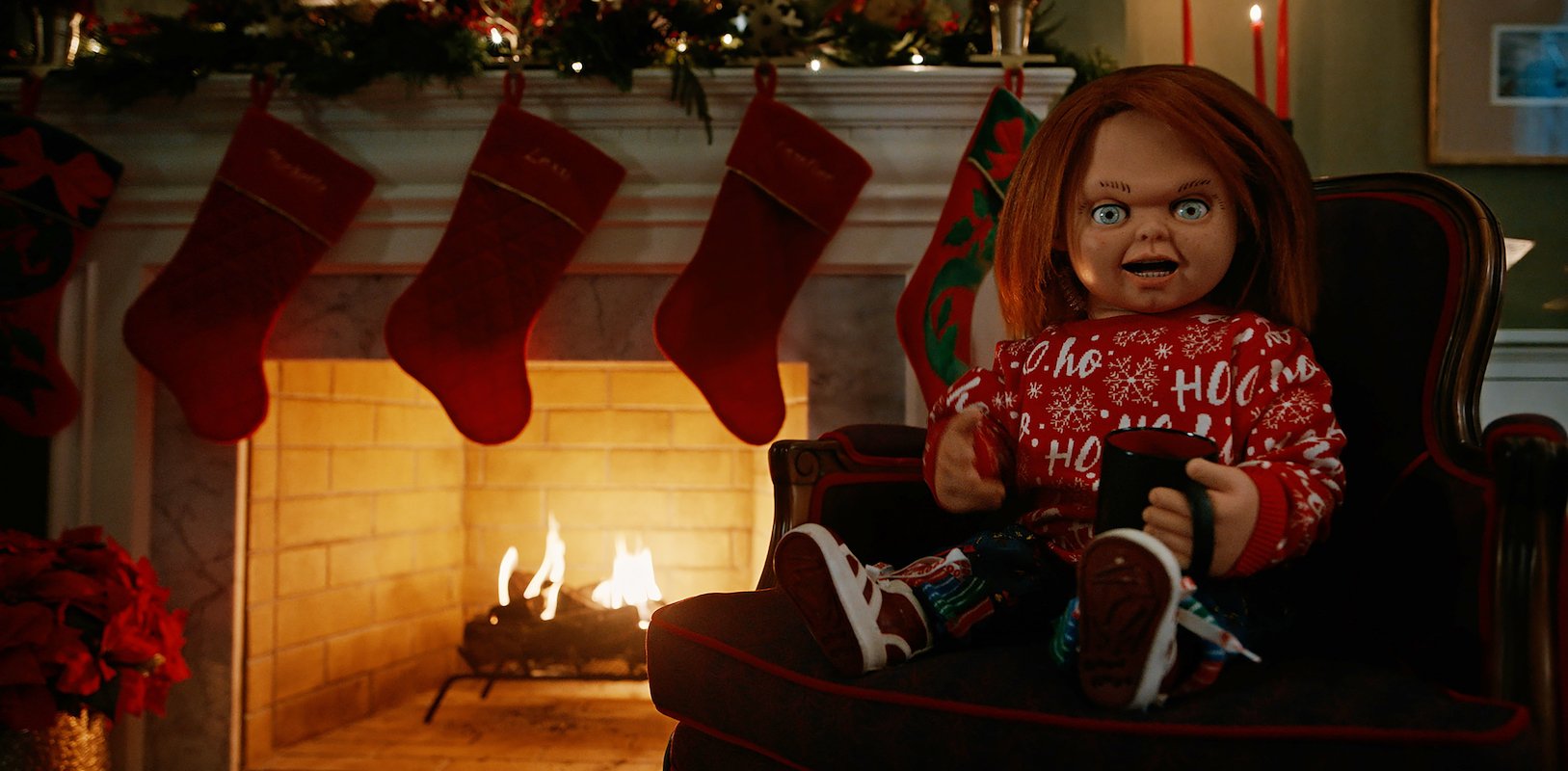 Chucky sits in front of a Christmas fire
