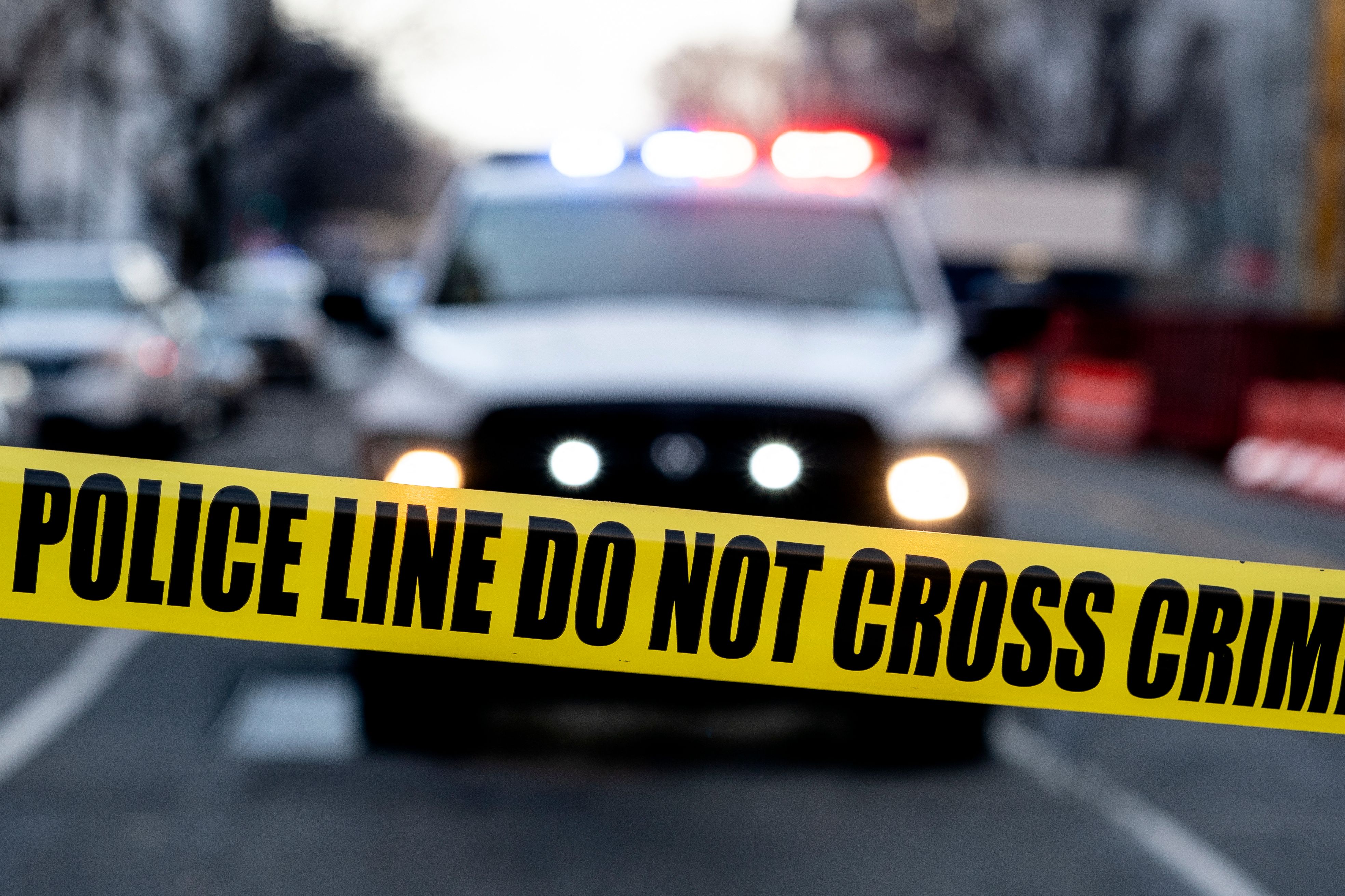 A police SUV is seen behind crime scene tape