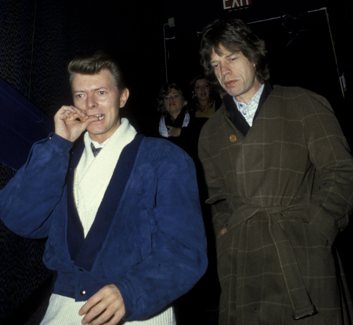 Musicians David Bowie and Mick Jagger walk by paparazzi in 1985