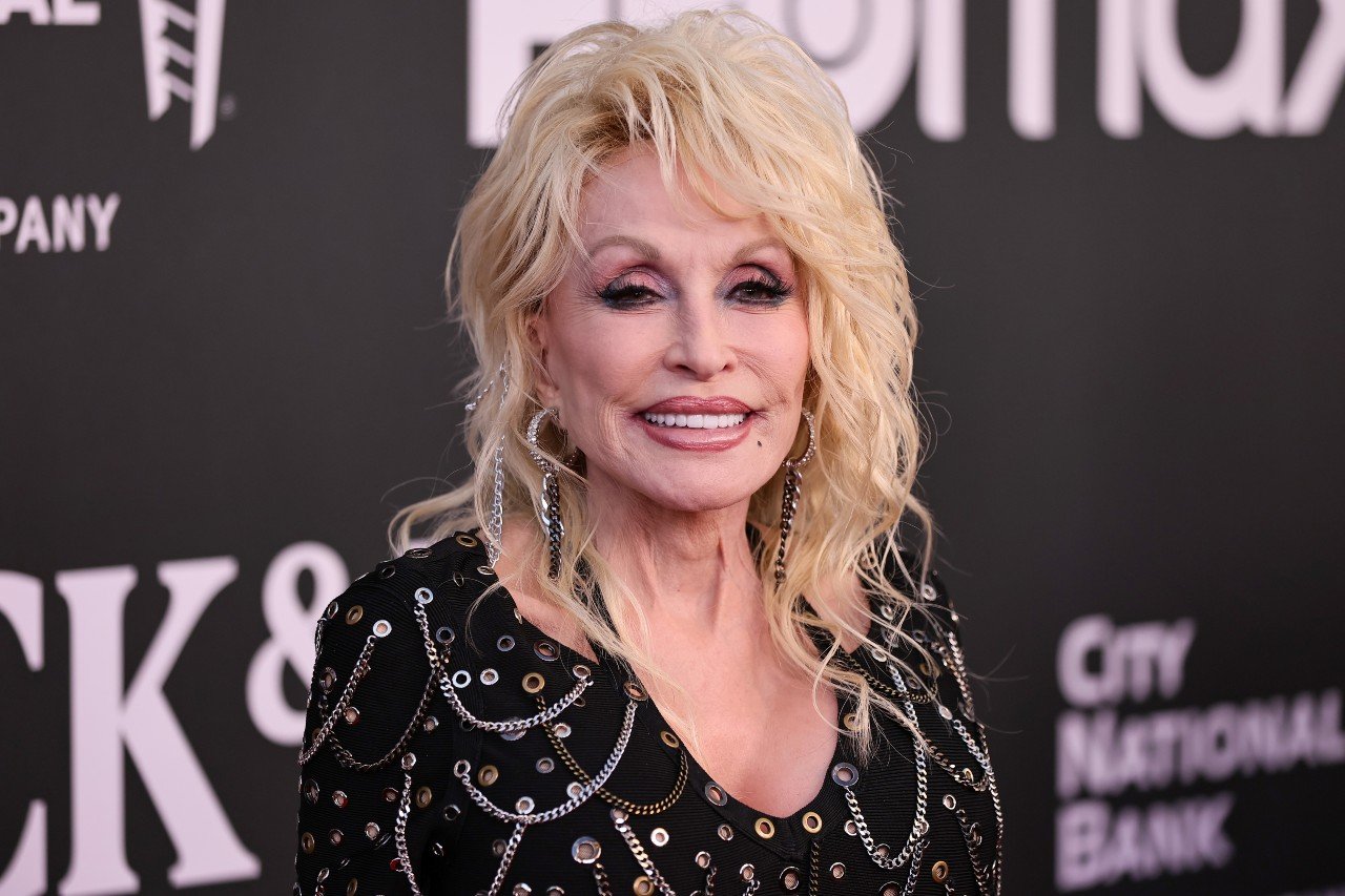 Dolly Parton smiles while wearing a black outfit with chains to the 37th Annual Rock & Roll Hall of Fame Induction Ceremony at Microsoft Theater.